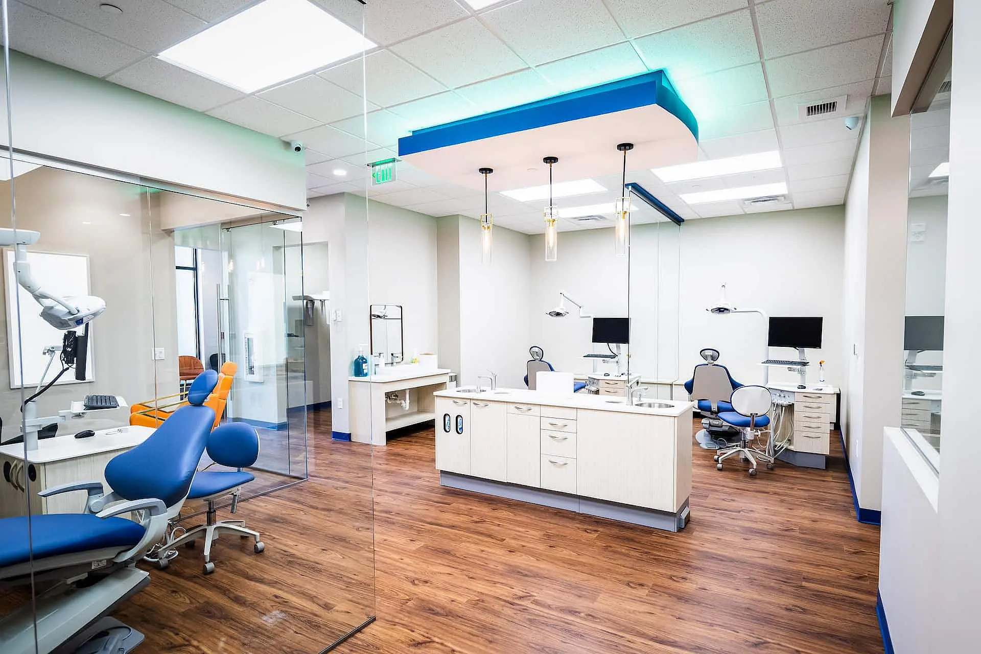 At Happy Smiles Orthodontics in St. Augustine, FL, the modern clinic features multiple dental chairs, advanced equipment, and monitors on sleek wood flooring, all enclosed by glass walls beneath bright overhead lighting.