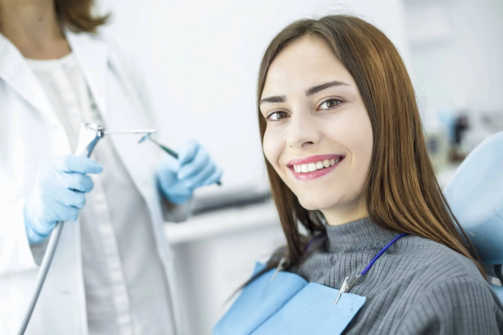 At Happy Smiles Orthodontics in St. Augustine, FL, a woman smiles in the dental chair after jaw surgery as her dentist stands nearby with dental instruments.