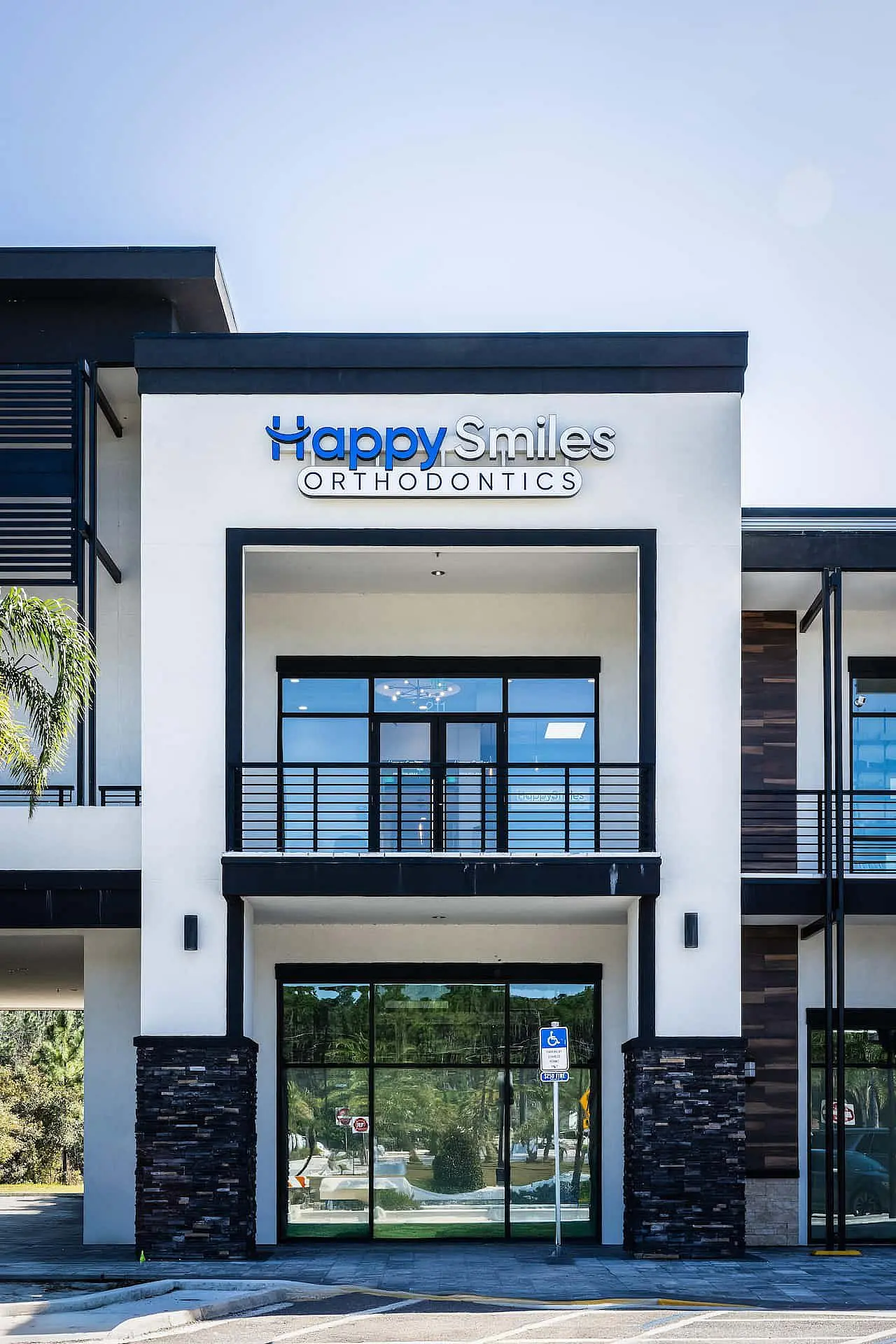 A modern two-story building with a glass entrance displays the "Happy Smiles Orthodontics" sign, home to a trusted orthodontist in St. Augustine, FL.
