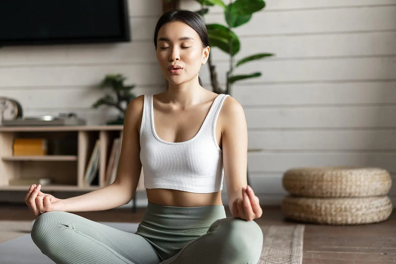 Meditation and other mindful habits, as shown by a woman sitting cross-legged in activewear, can help reduce the impact of mouth breathing on oral health and bad breath—an approach encouraged by Happy Smiles Orthodontics in St. Augustine, FL.
