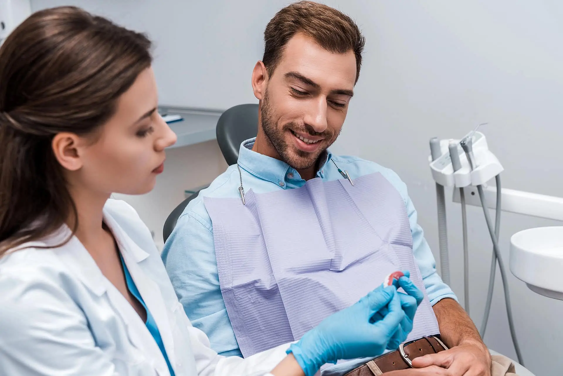 At Happy Smiles Orthodontics in St. Augustine, FL, a dentist explains adult orthodontic options to a patient while displaying a dental mold in the office.