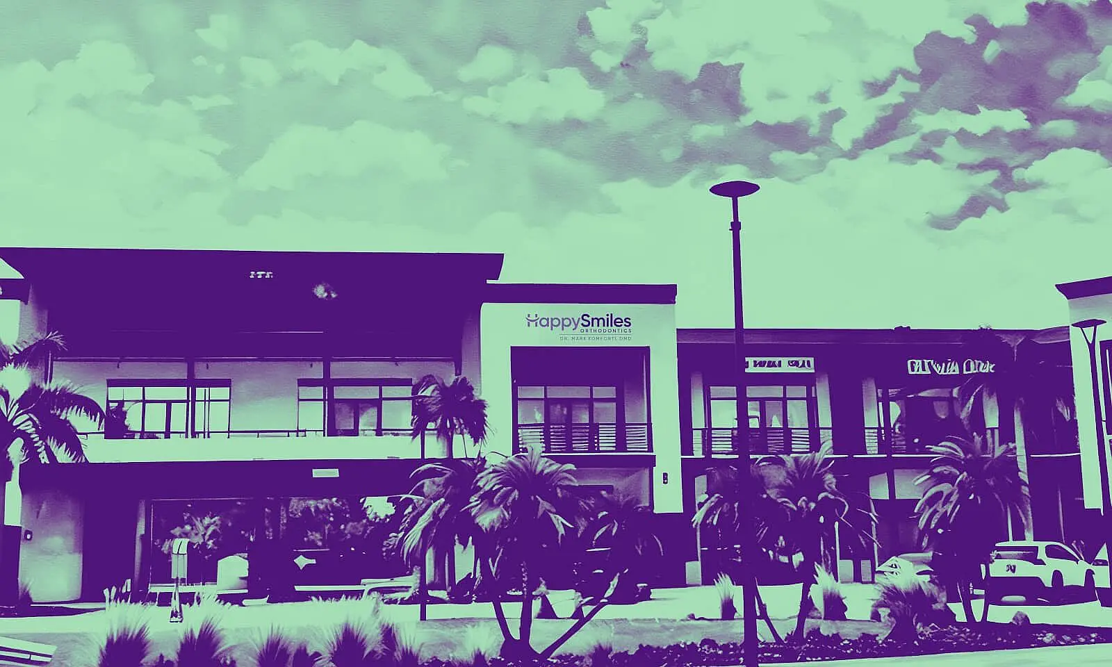 The modern commercial building in St. Augustine, FL features signs for Happy Smiles Orthodontics and Sushi Roll restaurant, set among palm trees beneath a partly cloudy sky.