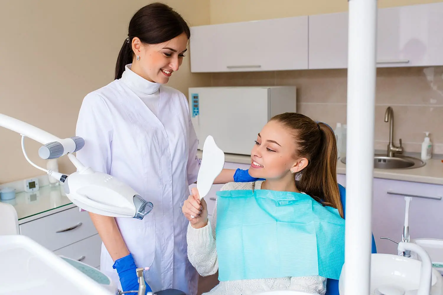 In St. Augustine, FL, Happy Smiles Orthodontics features a modern dental office where a dentist stands beside a patient seated in a dental chair, both smiling as they review results of specialized procedures like jaw surgery.