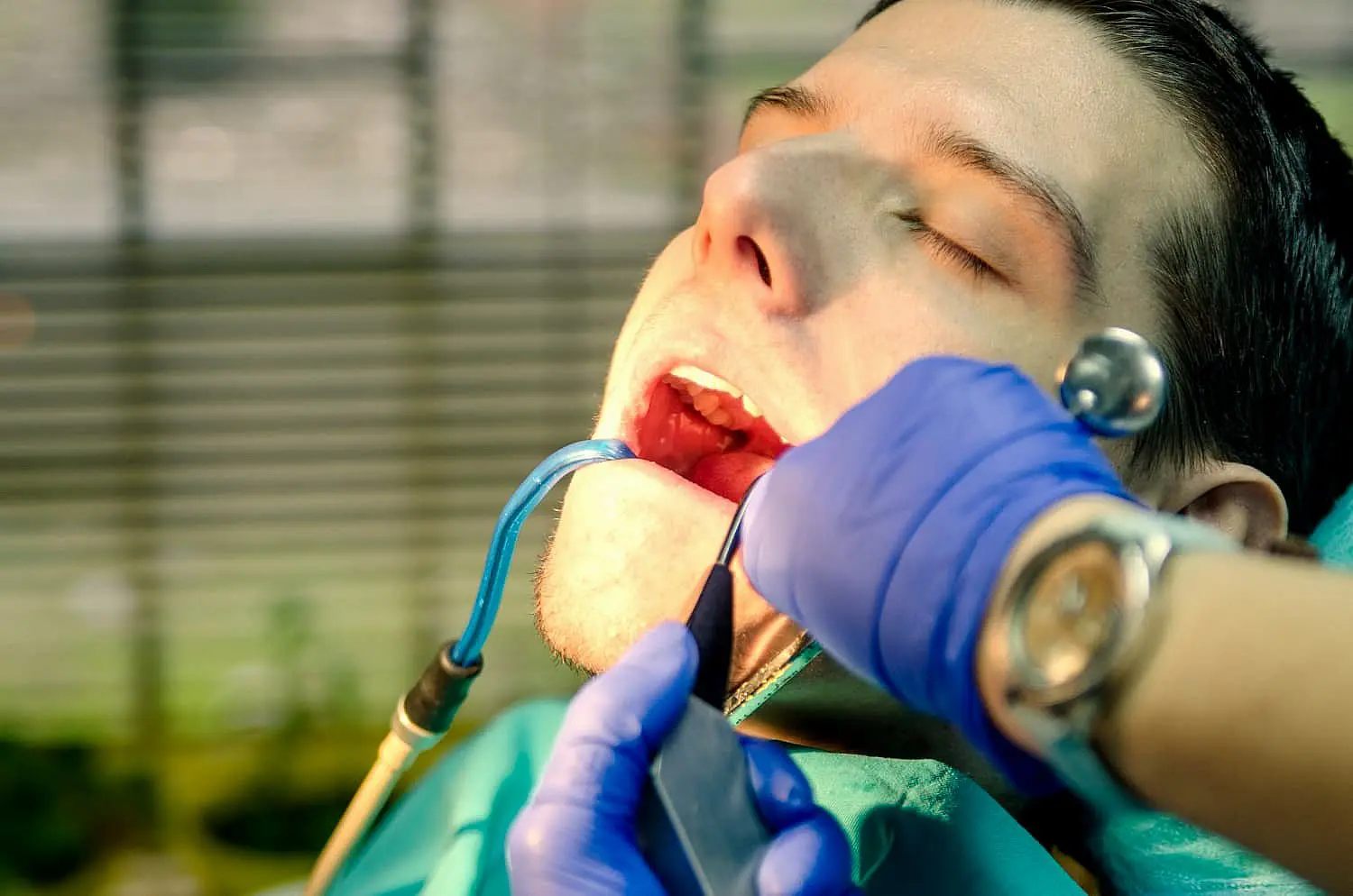 At Happy Smiles Orthodontics in St. Augustine, FL, a dentist wearing blue gloves examines a patient's teeth and checks for tongue thrust as the patient sits in the dental chair with their mouth open.