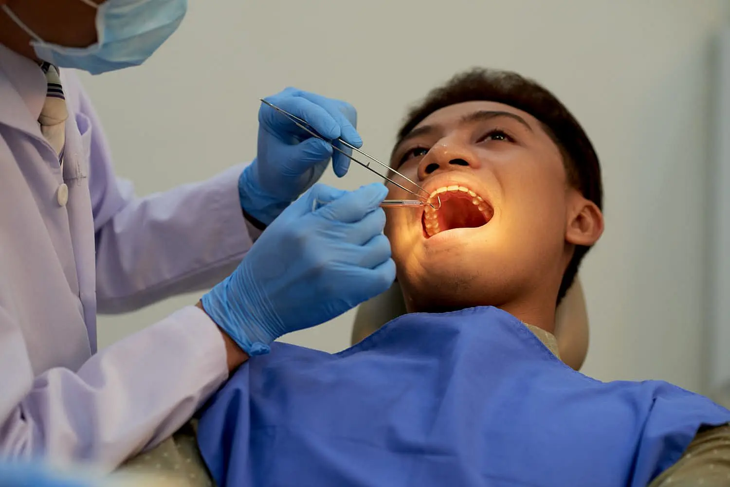 At Happy Smiles Orthodontics in St. Augustine, FL, a dentist wearing gloves uses dental tools to carefully examine a patient's mouth for issues such as an underbite while the patient is seated in the dental chair.