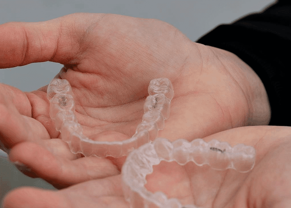 While considering options like the Invisalign Payment Plan, a person holds two clear aligners at Happy Smiles Orthodontics in St. Augustine, FL.