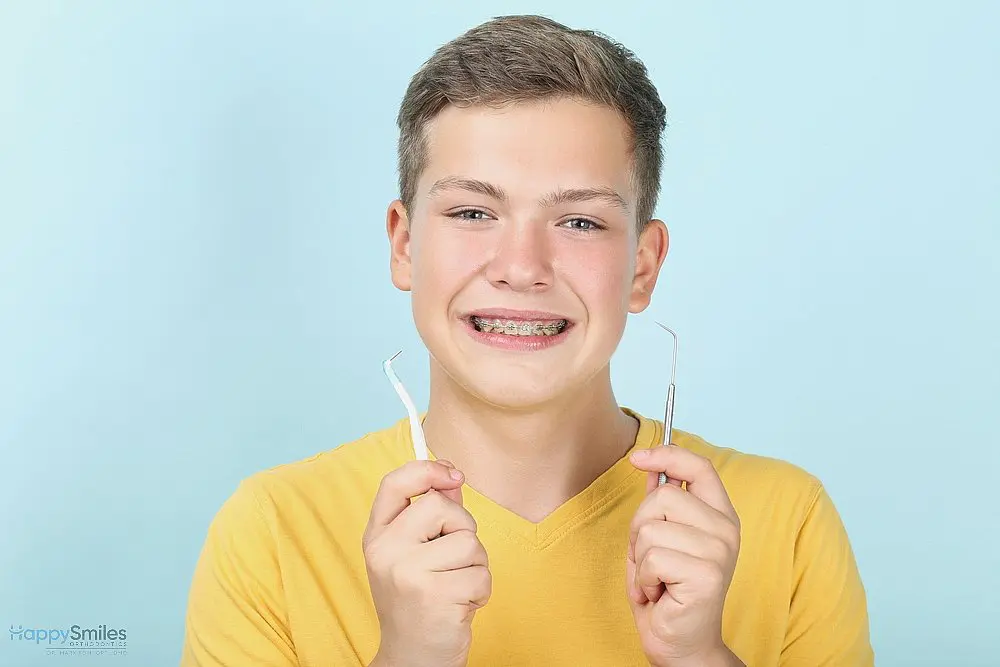 young man with metal braces toothbrush dentist tool - How to Floss with Braces in St. Augustine, FL