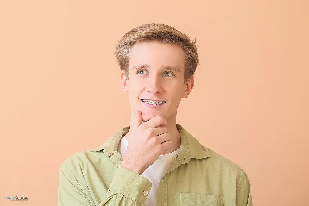 handsome man metal braces color background - How Long Do Braces Take in St. Augustine, FL 